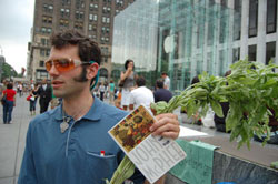 Daniel Bowman Simon, leader of Waiting for Apples, holds a stalk of fresh basil and a book outside of the Fifth Avenue Apple Store on Monday while talking with passers-by. His group, which is promoting sustainable agriculture, was already in line to be the first to purchase the iPhone 3G, which is scheduled to go on sale at 8:00 a.m. local time Friday.